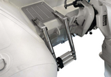 Close-up of a metallic ladder or stair attachment mounted on a white boat or vessel structure, with part of a white outboard motor visible.