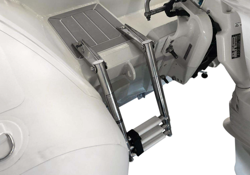 Close-up of a metallic ladder or stair attachment mounted on a white boat or vessel structure, with part of a white outboard motor visible.