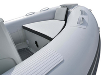 A close-up view of a white inflatable boat interior showing a padded bench seat, storage compartment, textured deck mat, and black trim details against a white background.